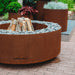 GrillSymbol Corten Steel Fire Pit Luna, ø 119 cm close up with logs