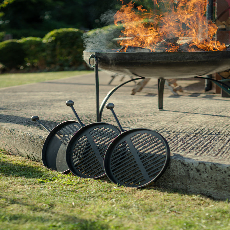 Plain Jane 120 Fire Pit with Four Swing Arm BBQ Racks Firepits UK bbq racks in front of lit fire pit