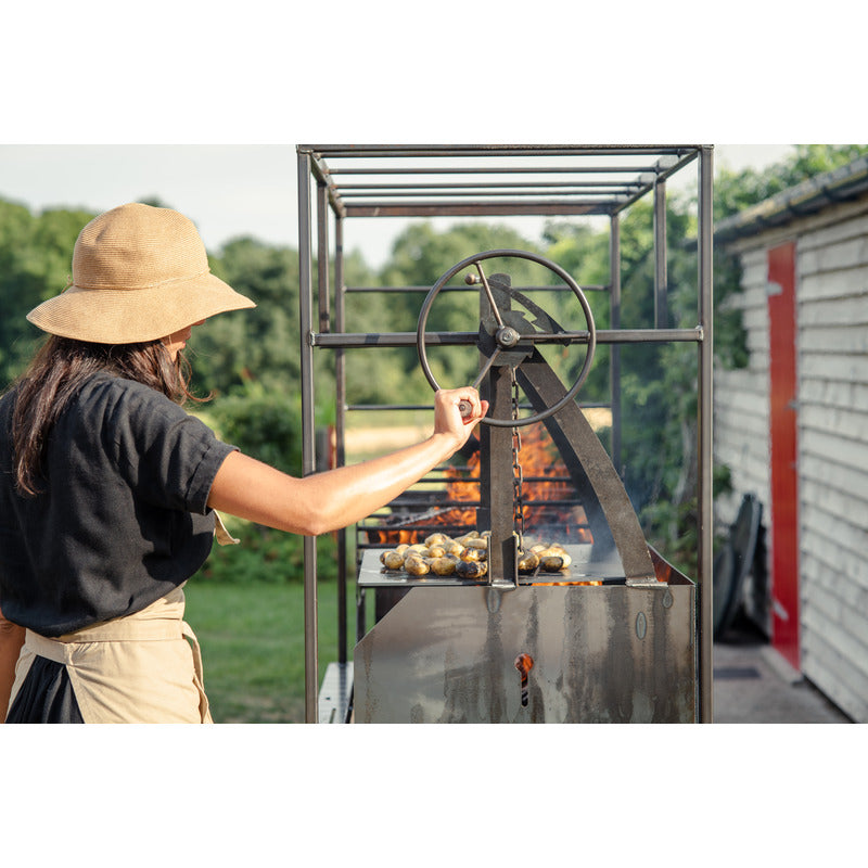 Asado Primera BBQ – The Banquet Firepits UK wheel BBQ lit cooking potatoes